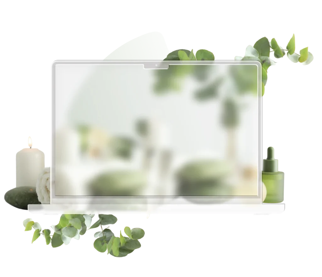 Laptop surrounded by spa foliage, candles and skincare products